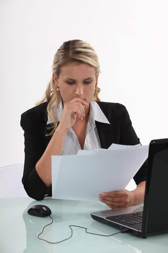 Business Woman Sitting at Laptop Reviewing Paperwork