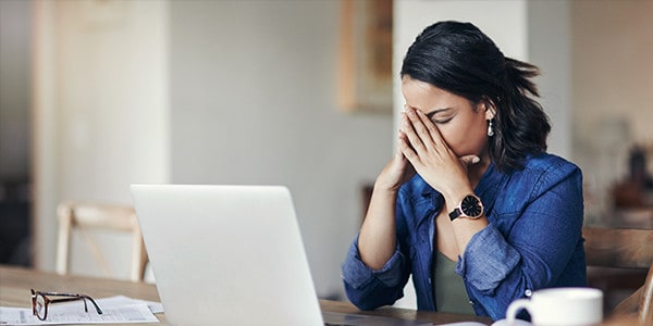 Mental Health in the Workplace - Worker With Hands on Face, Closed Eyes in Front of Laptop